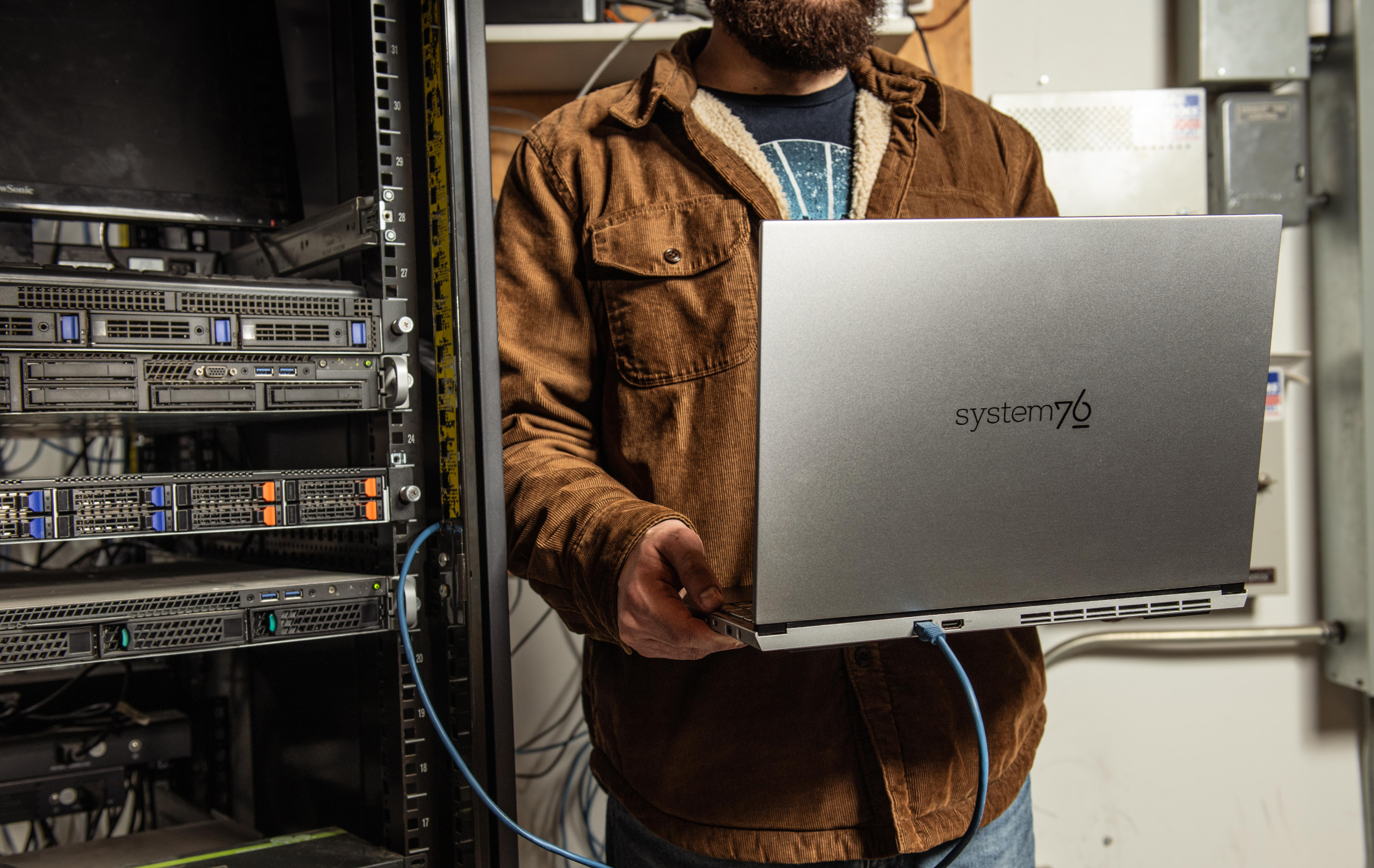 Systems engineer holding a Darter Pro laptop next to a server closet.